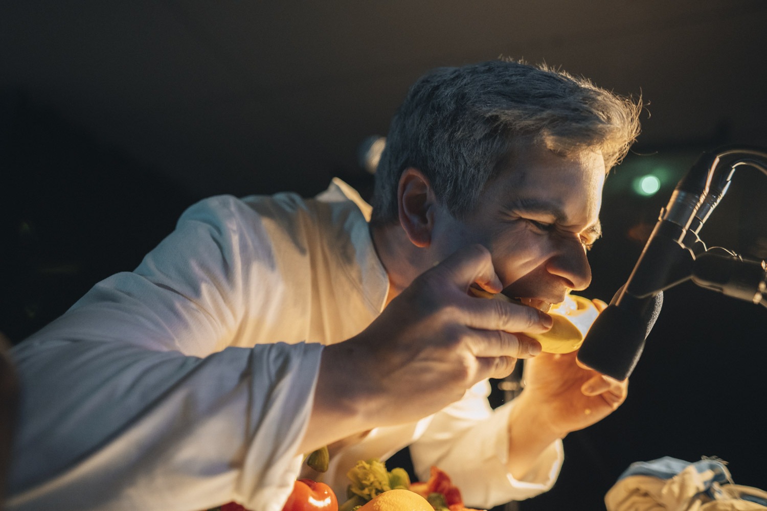 Detail muža zahryznutý do banána. Zvuk snímajú mikrofóny. Zvuky a ruchy vznikajú na princípe foley art.